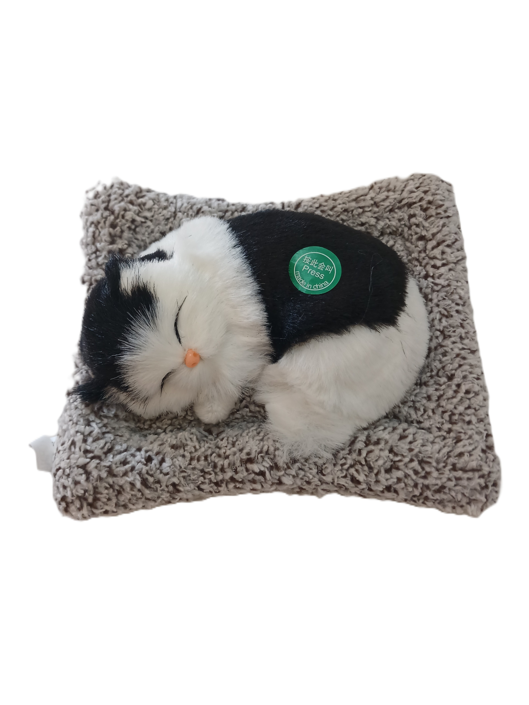 Plush meowing cat - toy on a textured pillow.